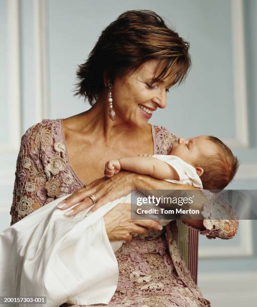 grandmother holding sleeping baby granddaughter (0-3 months) - baptism girl stock pictures, royalty-free photos & images