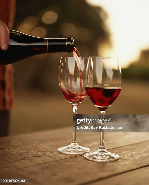 hand pouring red wine into glass - red wine glass stock pictures, royalty-free photos & images