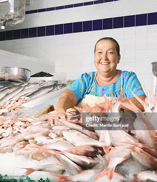 mature female fishmonger behind counter, smiling, portrait - fish vendor bildbanksfoton och bilder