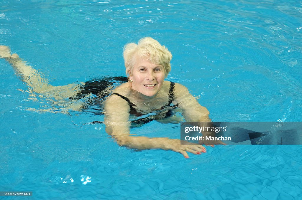 Senior woman in swimming pool, smiling, portrait