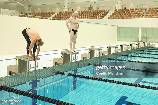 two senior men on diving boards, one preparing to dive - slip de bain de compétition photos et images de collection
