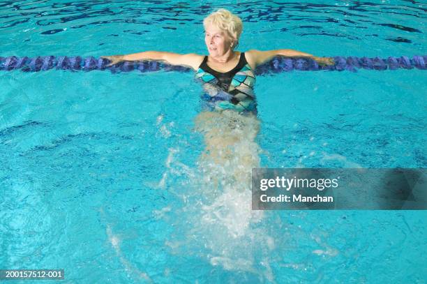 senior woman leaning on lane marker in swimming pool, elevated view - swimming lane marker foto e immagini stock