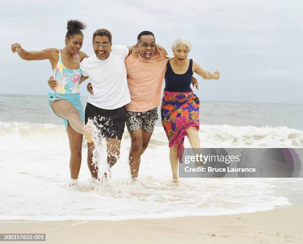 two mature couples running in surf at water's edge - skip stockfoto's en -beelden