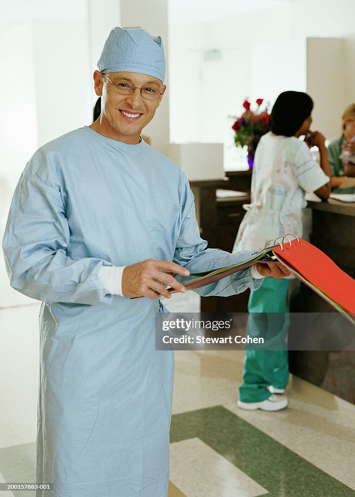 Mature surgeon in hospital scrubs holding patient chart