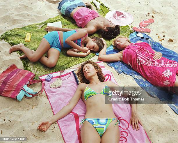 women and girl (10-12) lying on beach, eyes closed, elevated view - grandma sleeping stockfoto's en -beelden