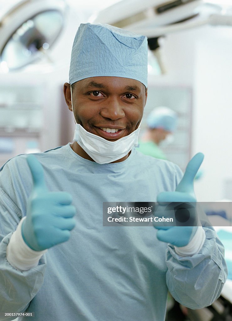 Surgeon giving 'thumbs up' sign in surgery room, portrait