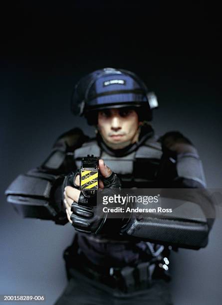young man wearing body armor, pointing stun gun (focus on stun gun) - betäubungsgewehr stock-fotos und bilder