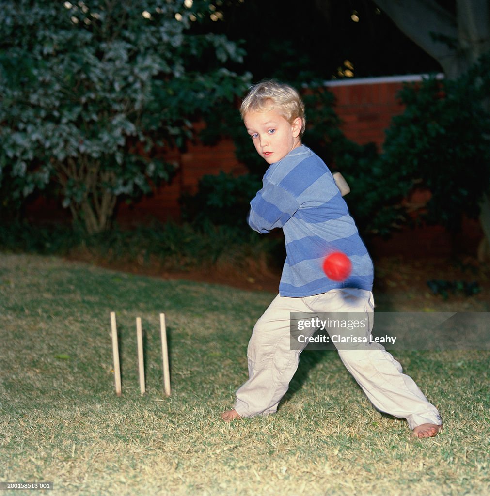 Young boy (4-6) playing cricket, ball in mid air