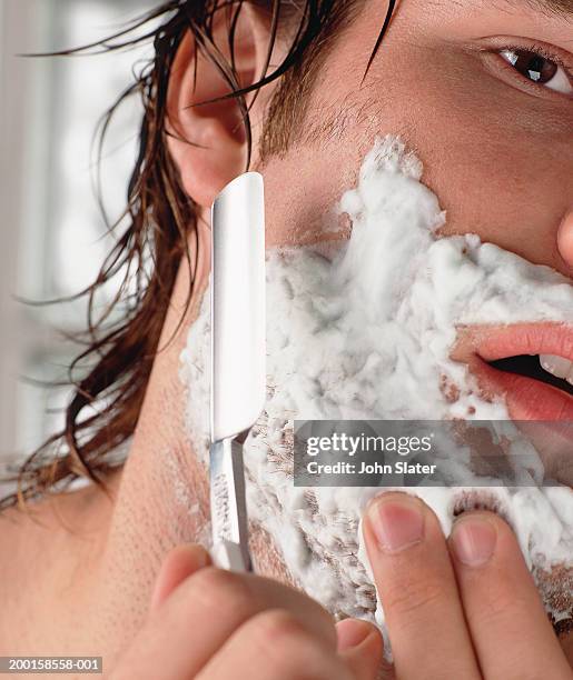 young man with wet hair, shaving using cut-throat razor, close-up - shaving foto e immagini stock