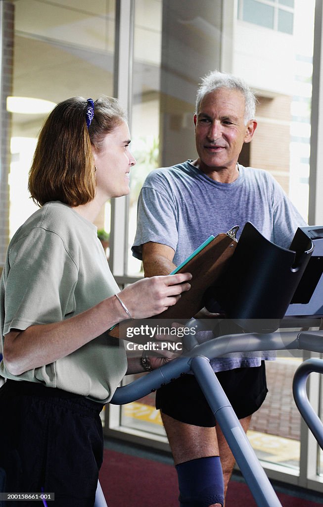 Physical therapist monitoring senior man on treadmill