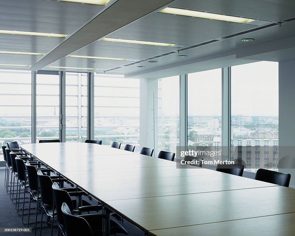 Boardroom table and chairs, by windows overlooking cityscape