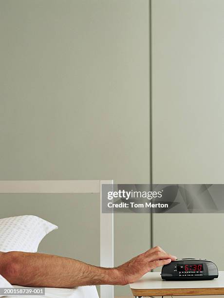 man in bed reaching for alarm clock - alarm clock on nightstand stock pictures, royalty-free photos & images