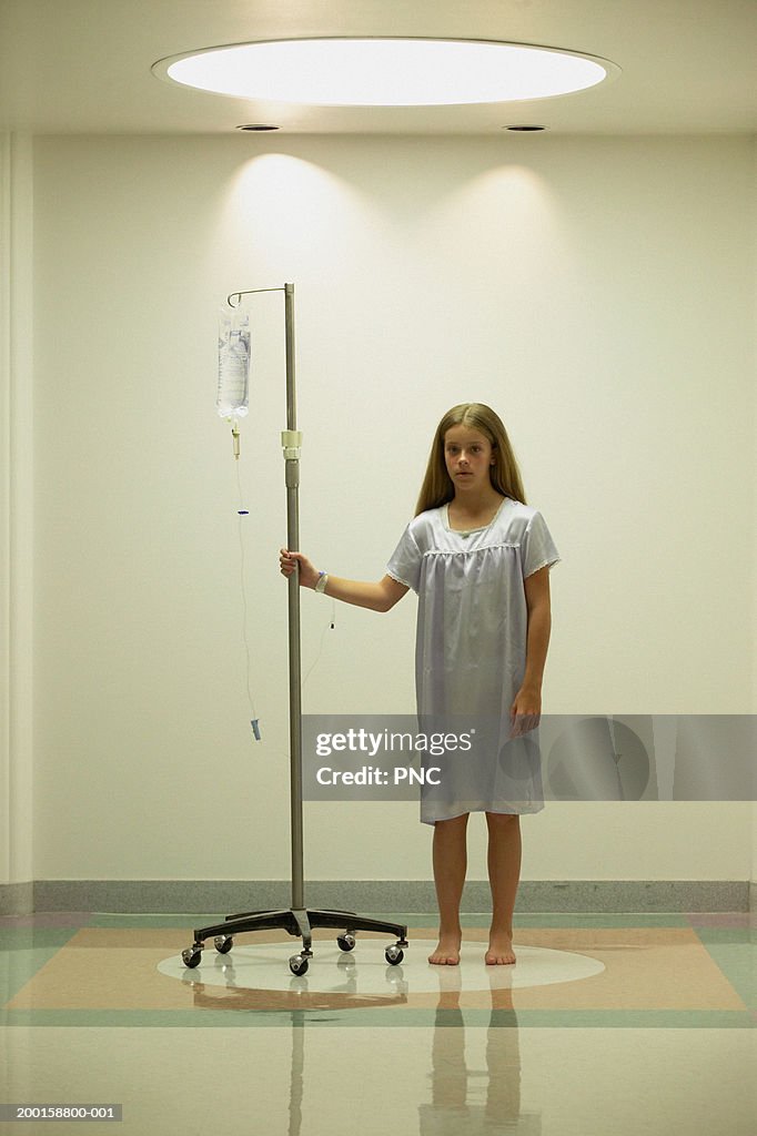 Girl (11-13) standing in hospital corridor with IV drip, portrait