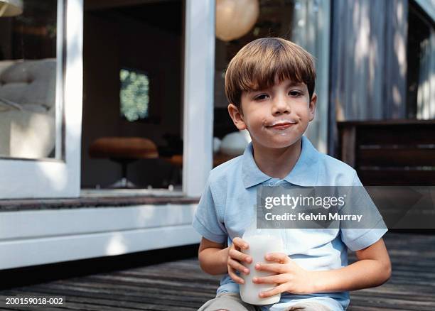 boy (6-8) with milk moustache, holding milk bottle, portrait - milk moustache stock-fotos und bilder