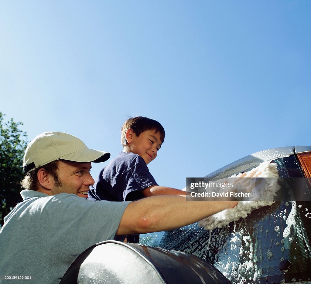 Man and boy (7-9) washing car, low angle view