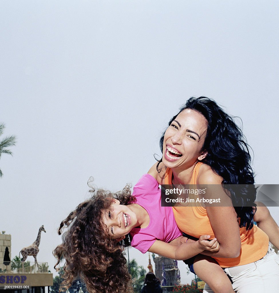 Mother carrying daughter (3-5), laughing