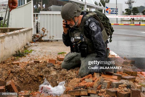 An Israeli policeman inspects the impact crater left by a rocket fired from southern Lebanon where it landed near the entrance of Ziv hospital in...