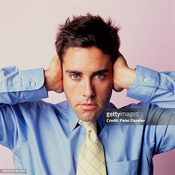 young man covering ears with hands, close up, portrait - hear no evil stock pictures, royalty-free photos & images