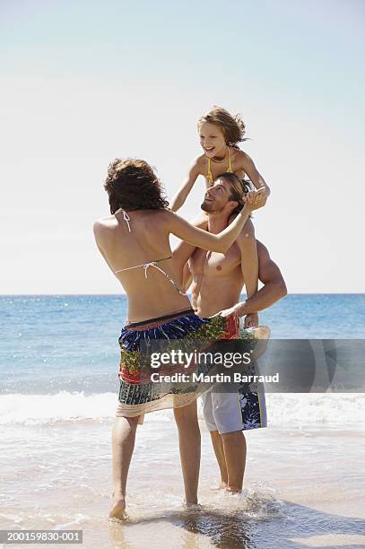 parents and daughter (8-10) on beach, girl on man's shoulders - travel11 stock pictures, royalty-free photos & images