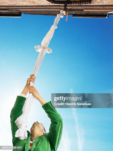 man clutching knotted sheets hanging from window, low angle view - drap photos et images de collection