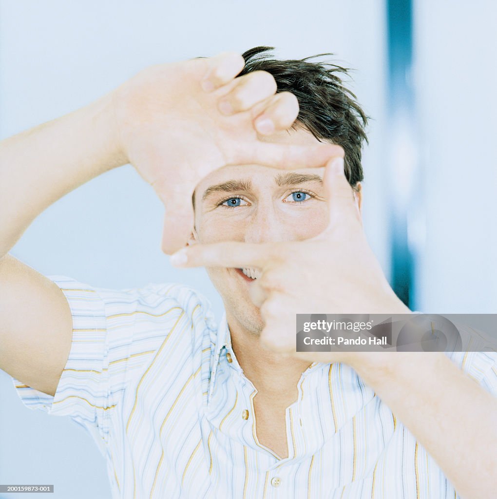 Man looking through square shape created with hands, portrait