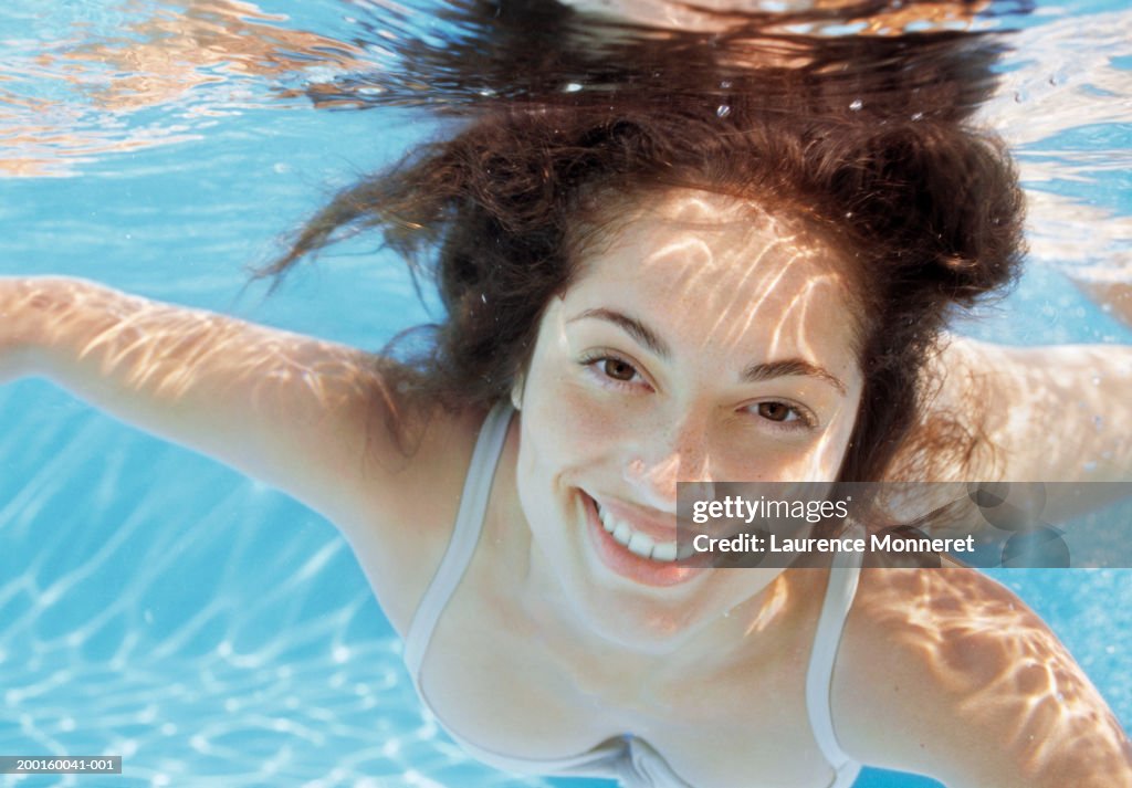 Young woman in swimming pool, portrait, underwater view