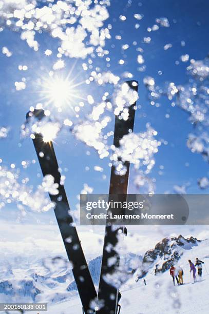 pair of skis upright on slope, skiiers in background - espace killy stock pictures, royalty-free photos & images
