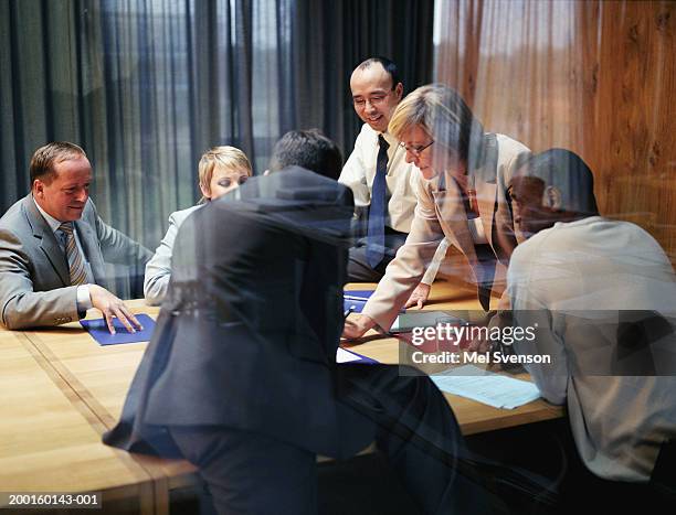 mature businesswoman conducting meeting, view through window - réunion du personnel photos et images de collection