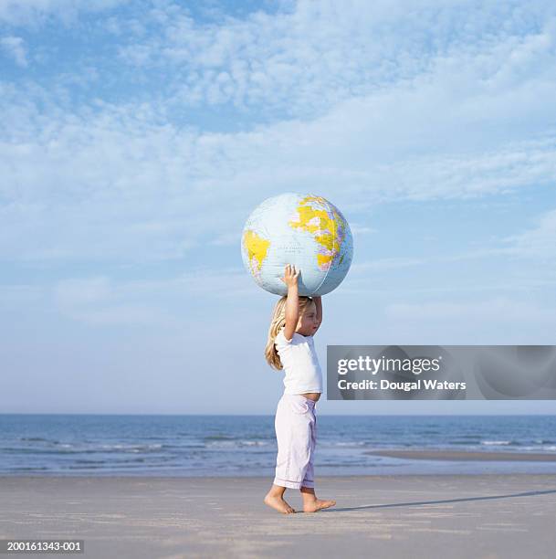 girl (2-4) on beach  carrying inflatable globe on head, side view - world children day stock pictures, royalty-free photos & images