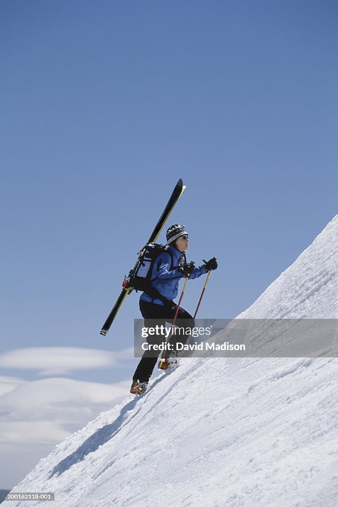 Female Backcountry Skier Climbing Up Snow Covered Mountain Side