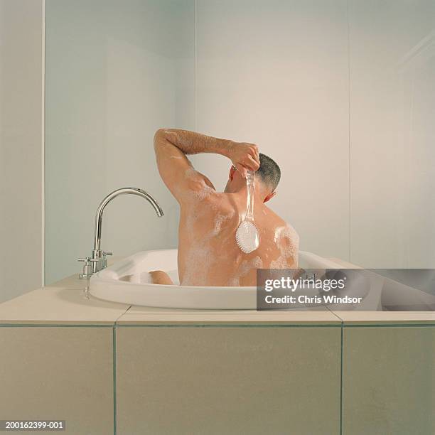 man in bath using back brush, rear view - homem banho imagens e fotografias de stock