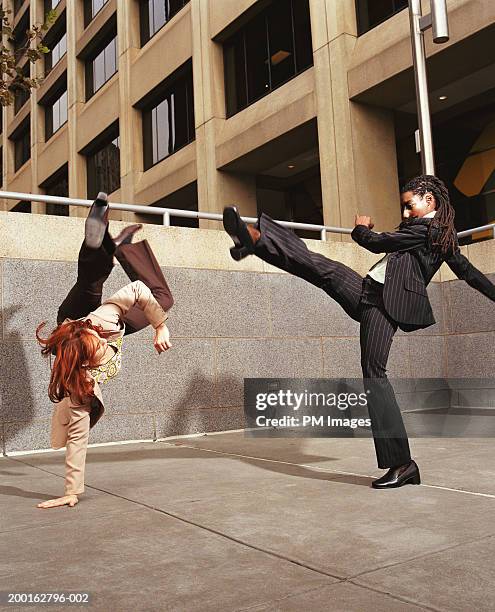 two businesswomen fighting (capoeira) in office plaza - businesswoman handstand stock pictures, royalty-free photos & images