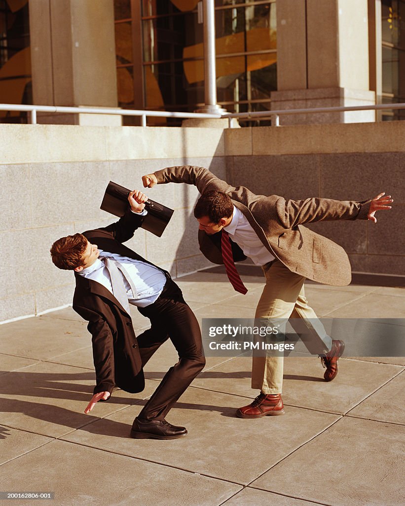 Two businessmen fighting in office plaza