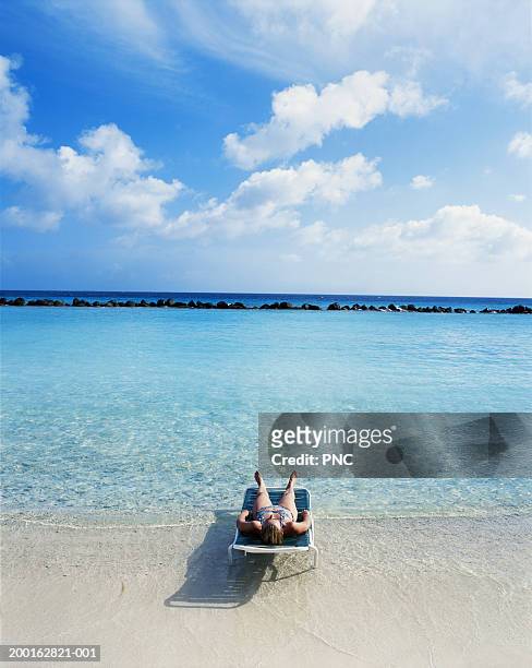 leeward dutch antilles, aruba, woman lying on tropical beach - aruba beach stock-fotos und bilder