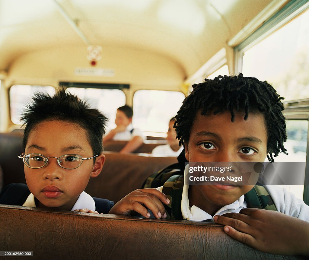 Two boys (5-7) on school bus, portrait