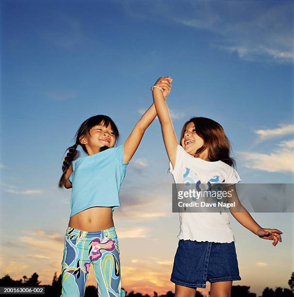 two girls (5-7) smiling, holding hands - stoneplus8 stock pictures, royalty-free photos & images