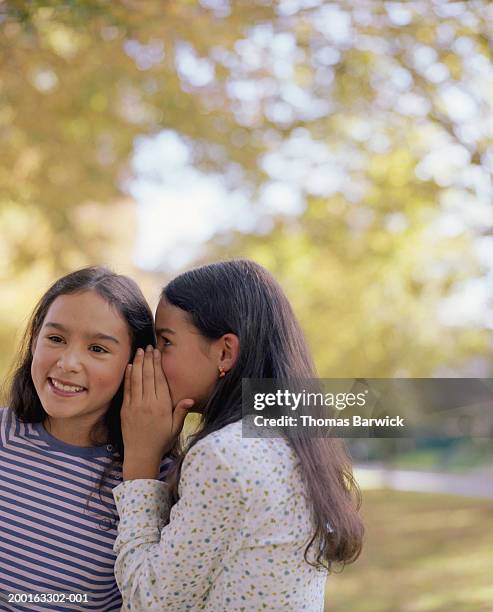 girl (9-11) whispering in twin sister's ear - child whispering stock-fotos und bilder