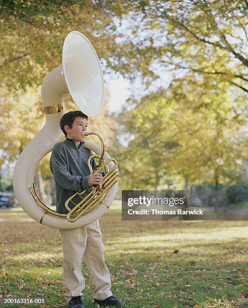 boy (8-10) standing in field, playing tuba, autumn - tube foto e immagini stock