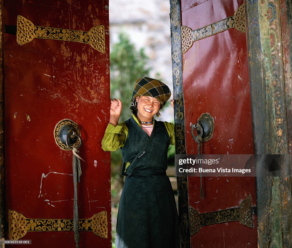 China, Tibet, Lhasa, woman at open door smiling, portrait