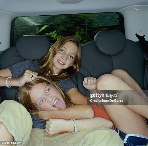 two sisters (9-11) play fighting in backseat of minivan, portrait - play fight stock pictures, royalty-free photos & images