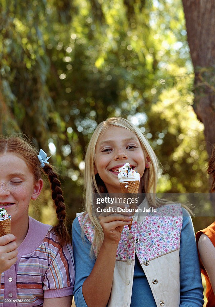 Children (8-10) eating ice cream outdoors, portrait, close-up