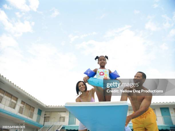 girl (4-6) with inner tube on diving board,  parents watching - jump in pool stock pictures, royalty-free photos & images