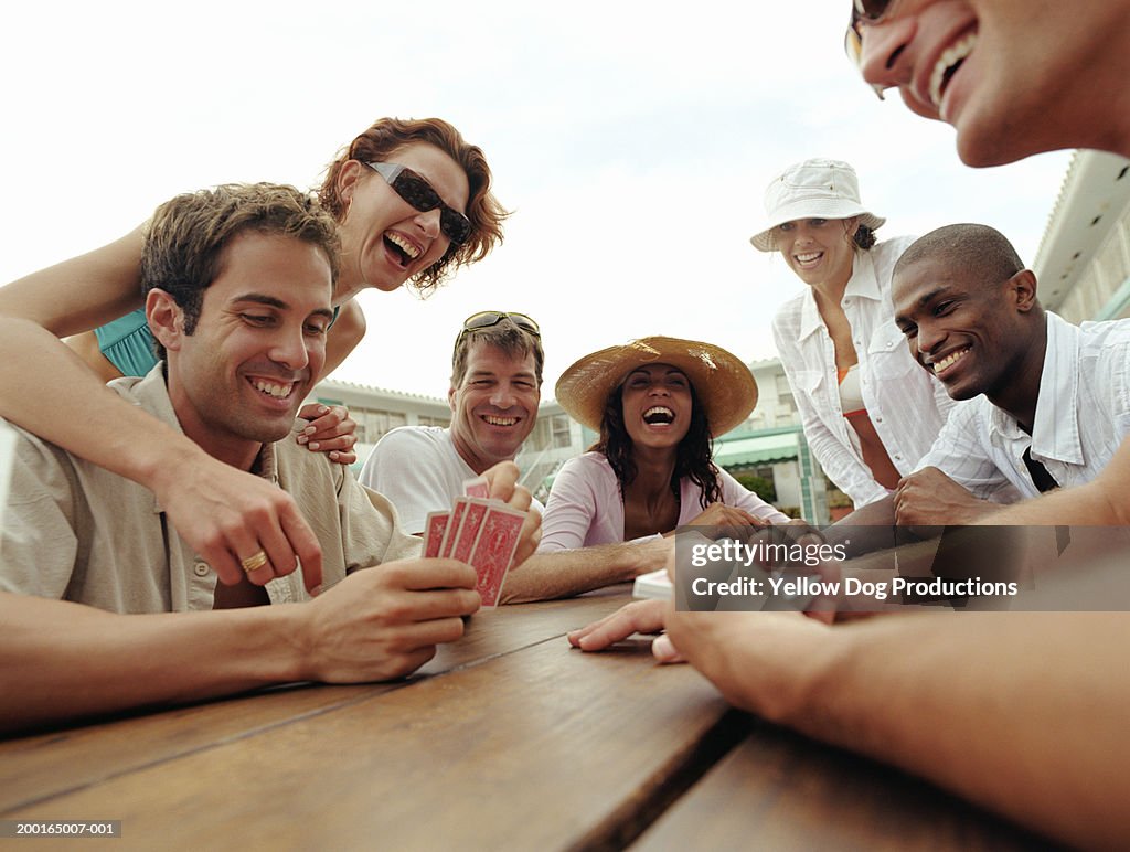 Group of adults playing cards by poolside of hotel