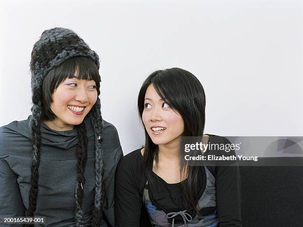 two young women sitting on sofa, looking at each other - stoneplus9 ストックフォトと画像
