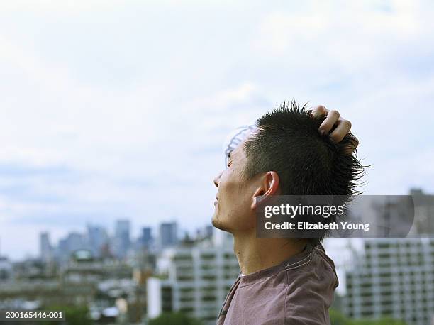 man on roof of building, hand on head, side view - stoneplus9 ストックフォトと画像