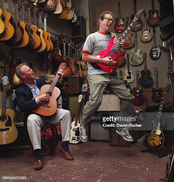 two men playing guitars in guitar shop - musikgeschäft stock-fotos und bilder