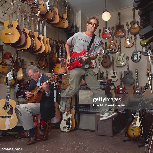 two men playing guitars in guitar shop - guitar shop stock pictures, royalty-free photos & images