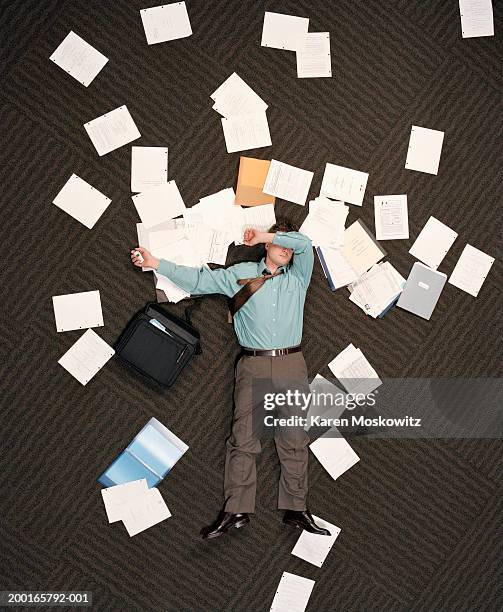 businessman lying on ground littered with paper, overhead view - project failure stock pictures, royalty-free photos & images