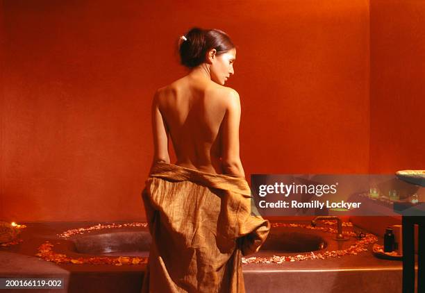 woman by bath surrounded by rose petals and candles, rear view - robe rose stock pictures, royalty-free photos & images