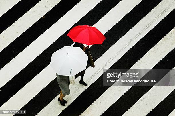 people carrying umbrellas, crossing street at crosswalk, elevated view - umbrellas from above photos et images de collection